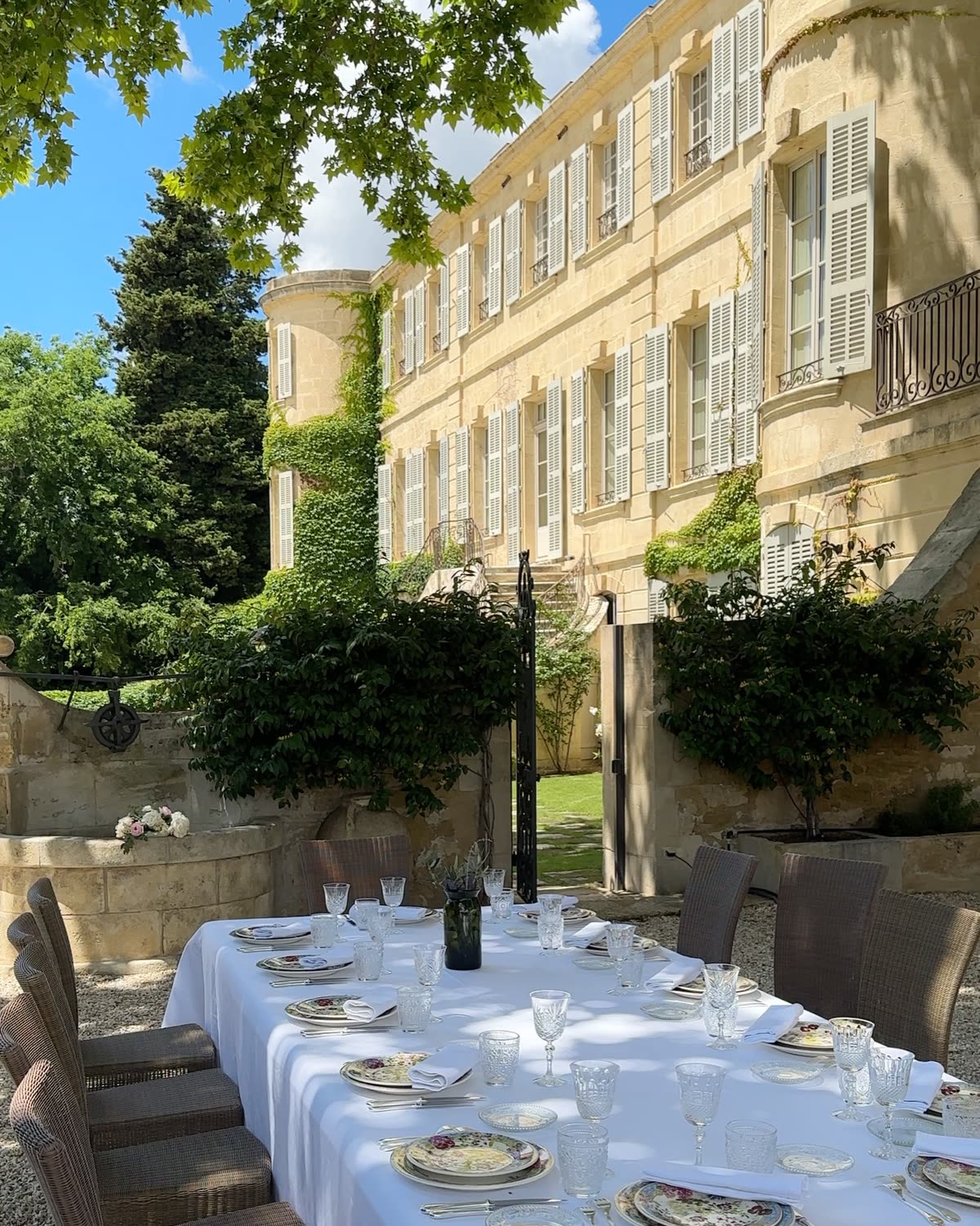 A long table set for lunch in the garden of Château d’Estoublon, Provence, under the château’s shuttered façade